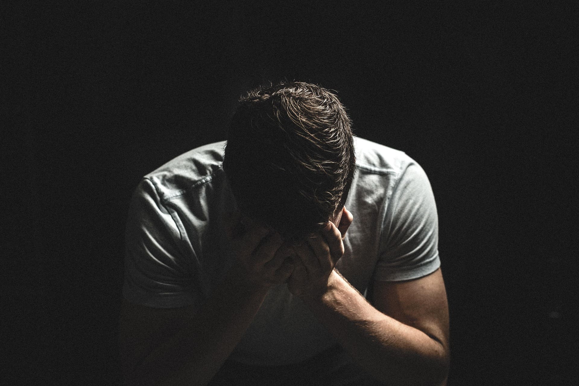 Homme seul, la tête entre les mains, illustrant la détresse et l’isolement pouvant accompagner les violences psychologiques et conjugales.