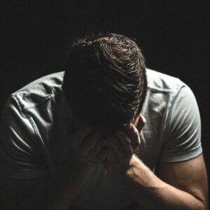 Homme seul, la tête entre les mains, illustrant la détresse et l’isolement pouvant accompagner les violences psychologiques et conjugales.